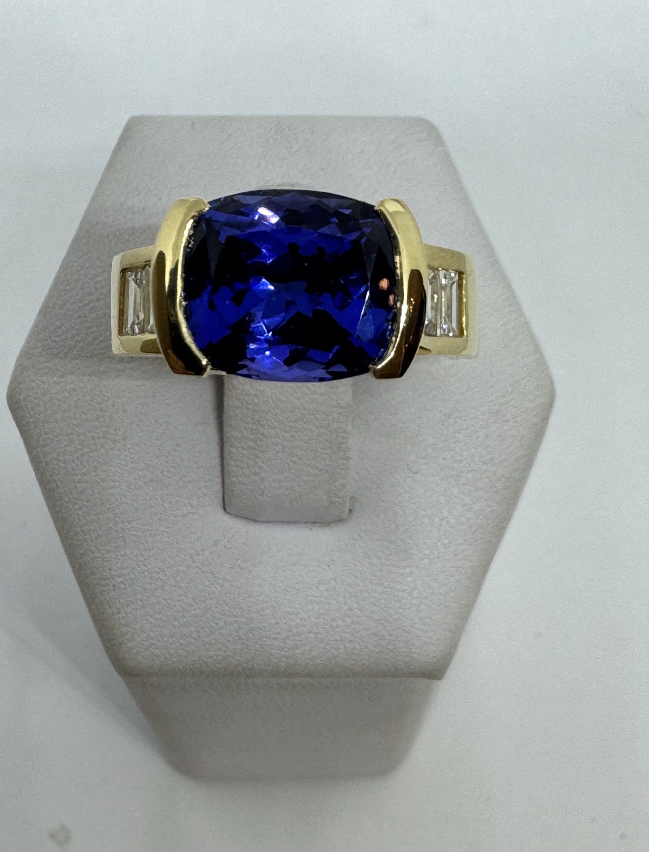 Cushion-cut blue gemstone ring with baguette diamonds in yellow gold